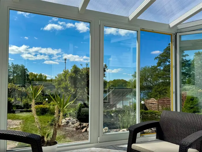 Helle Fensterfront mit weißen Rahmen und Blick in den Garten